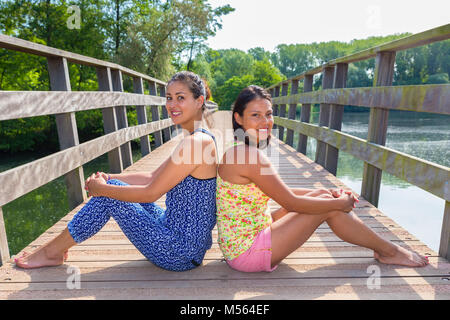 Zwei Freunde sitzen zusammen auf hölzerne Brücke in der Natur Stockfoto