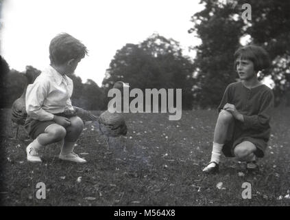 1920s, historische Bild zeigt einen kleinen Jungen und Mädchen in einem Feld mit einer Wildente angesprochen wurde, England, UK. Die junge Frau scheint leicht besorgt über diese. Stockfoto