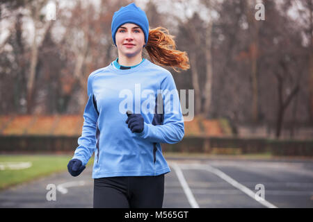 7/8 Schuß einer glücklichen jungen Frau läuft im Freien. Stockfoto