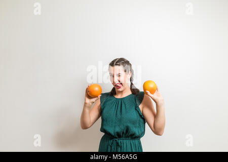 Schöne jugendlicher Mädchen macht die lustigen Gesichter beim Essen der Früchte Stockfoto