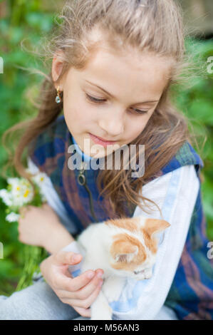 Schöne Mädchen mit einem Strauß Blumen und kleine Katze auf ihre Hände Stockfoto