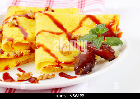 Pfannkuchen mit Walnüssen und Termine mit Datum Sirup auf weiße Platte gekrönt Stockfoto