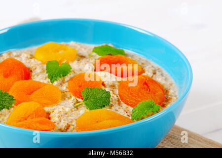 Schüssel Haferbrei Porridge mit getrockneten Aprikosen auf beige Unterlage - Nahaufnahme Stockfoto