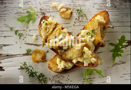 Gelbe Austernpilze in Butter gebraten, serviert mit Scambled Ei auf Sauerteig Toast mit wilde Rauke Stockfoto