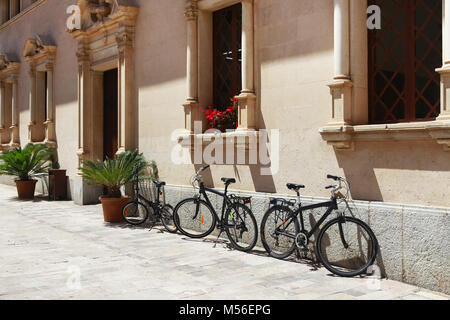 Abgestellte Fahrräder in der Nähe von einem schönen Gebäude in Alcudia, Spanien Stockfoto