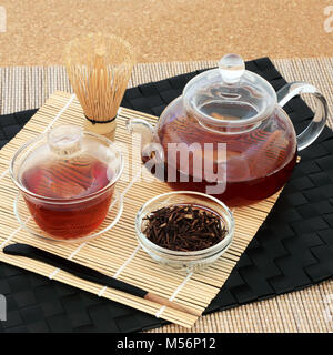 Kuchika Japanische gerösteten grünen Zweig Kaffee für gute Gesundheit mit Glas Teekanne und Tassen, getrocknete Zweige, Rührer und Schneebesen auf Bambus und Kork. Stockfoto