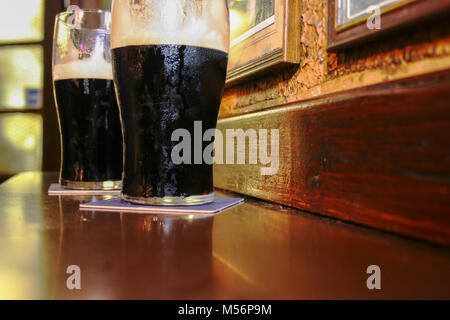 Zwei Gläser der berühmten schwarzen Irish Stout im Irish Pub auf Holzstab Stockfoto