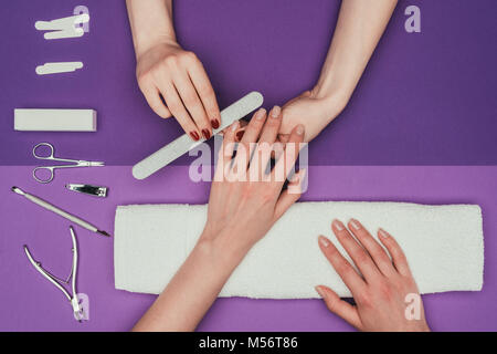 Zugeschnittenes Bild von Nail Technician feilen Nägel an Kunden mit Nagelfeile Stockfoto