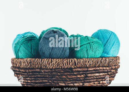 Blau und Grün warme Garn Kugeln im Weidenkorb auf Weiß Stockfoto