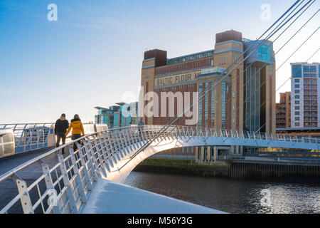 Newcastle upon Tyne, einem jungen Paar, zu Fuß über die Millennium Bridge in Richtung der Baltischen Zentrum für Zeitgenössische Kunst in Gateshead, England, Großbritannien Stockfoto