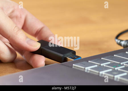 Eine weibliche Hand mit einem USB-Flash Laufwerk, bevor das Silber Laptop Stockfoto