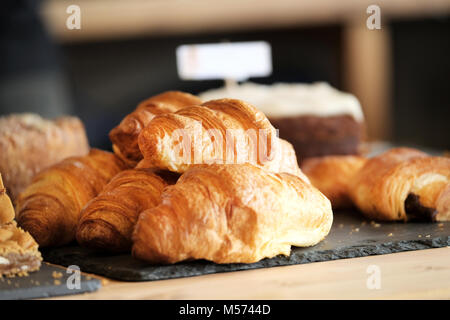 Frisch gebackene, golden, Butter, Croissants zum Verkauf auf einer Schiefertafel Zähler nach oben in einem Cafe Feinkost in Poole, Großbritannien angezeigt Stockfoto