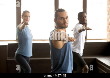 Gruppe der sportliche Menschen im Krieger zwei Übung stehend Stockfoto