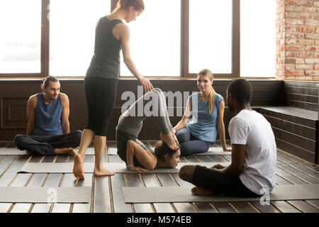 Weibliche Kursleiter hilft mit Ganda Bherundasana darstellen Stockfoto