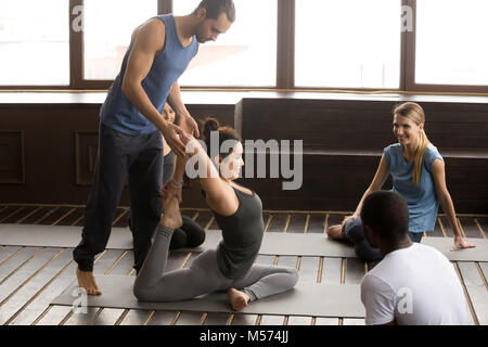 Kursleiter helfen, flexible Frau Yoga Übung in der Gruppe C Stockfoto