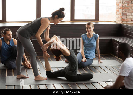 Weibliche Yoga Lehrer helfen Frau Übung in Gruppe tra tun Stockfoto