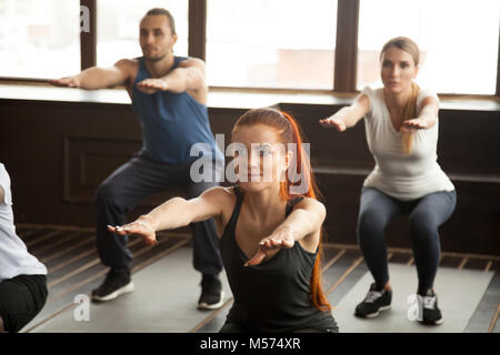 Sportliche junge Menschen tun Hocke Übung im Group Fitness Training". Stockfoto