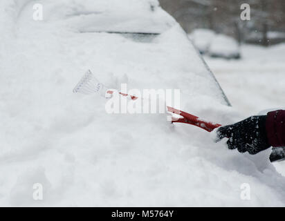 Eine Frau benutzt ein Eiskratzer, um Schnee und Eis im Winter von ihrem Auto  Windschutzscheibe zu entfernen. Warminster, Wiltshire, Vereinigtes  Königreich Stockfotografie - Alamy