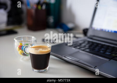 Tasse Kaffee und tasse farbige Schokolade Süßigkeiten neben einem Laptop, der perfekte snack Kombination für Arbeit Stockfoto