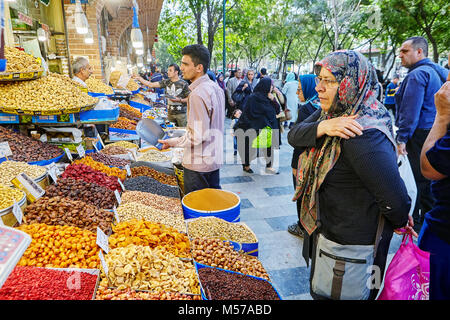 Teheran, Iran - 29. April 2017: ein ladenbesitzer Verkauf von getrockneten Früchten in der Teheraner Basar und Ältere muslimische Frau mit Kopftuch in der Nähe von ihm angezogen. Stockfoto