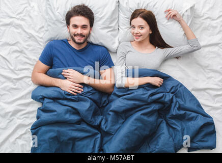 Junges Paar im Bett Top View morgen Konzept suchen Kamera lächeln Stockfoto