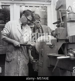 1968, historische, South London, England, junger Teenager Junge an einer staatlichen Schule mit Internat in einem Workshop mit einem Lehrer mit einer Latte während einer metallarbeiten Klasse. Stockfoto