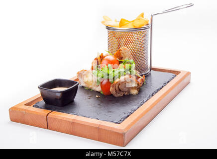 Spieße mit Fleisch mit Sauce und Kartoffeln Pommes frites in einem Eimer auf Holz Schneidebrett. Stockfoto