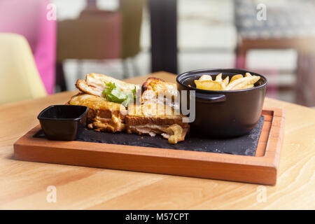 Club Sandwich mit Käse, Gurke, Tomate, geräuchertem Fleisch und Wurstwaren. Serviert mit Pommes Frites. Stockfoto