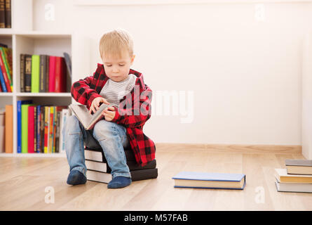 Drei Jahre altes Kind unter Bücher zu Hause sitzen Stockfoto