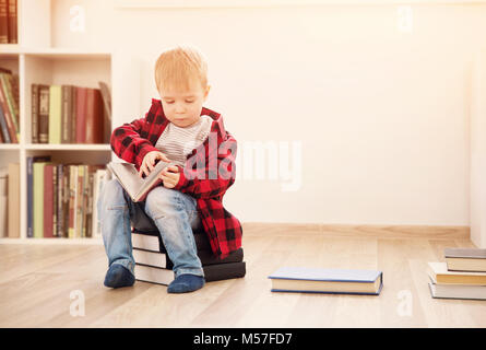 Drei Jahre altes Kind unter Bücher zu Hause sitzen Stockfoto