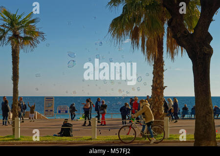 Menschen zu Fuß auf der Promenade des Anglais in Nizza im Winter (2018), in eine Wolke von Seifenblasen. Karneval. Stockfoto