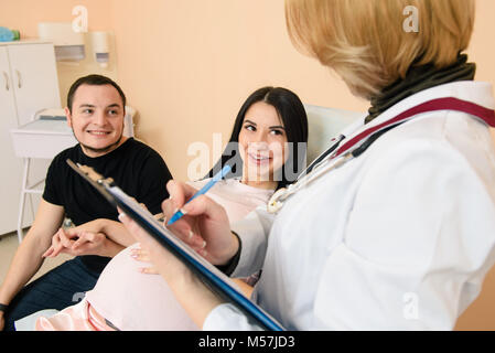 Junge schwangere Frau und ihr Ehemann lächeln in der Klinik. Glückliches Paar erwarten Baby besuchen Arzt. Stockfoto
