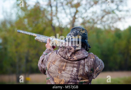 Horizontale Bild des Menschen trap Schießen in Camo mit Schrotflinte. Tontauben.. trap Shoot, Hut, lange Waffe Stockfoto