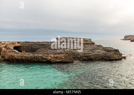 Den Sonnenuntergang und ein Felsbrocken im Wasser des Mittelmeers vom Caló des Moro auf der Insel Mallorca, Spanien gesehen. Stockfoto