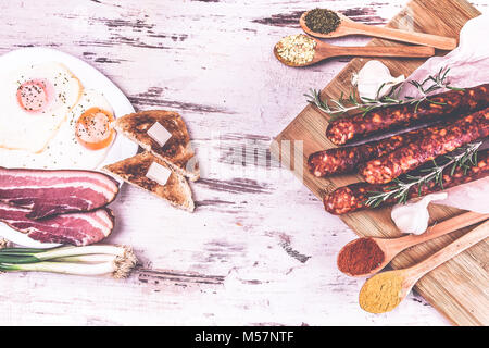 Speck, Würstchen und Spiegeleier auf einem hölzernen rustikalen Hintergrund. Sehr leckeres Essen. Ansicht von oben. Stockfoto