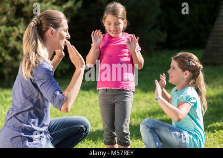 Glückliche Mutter mit Kindern Töchter tun Tanz Übung im Freien Stockfoto