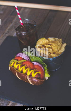 Lecker Hot Dog mit Belag auf dunklem Hintergrund. Tischplatte, Seitenansicht. Stockfoto