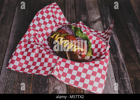 Classic Hot Dog mit Belag auf dunklem Hintergrund. Tischplatte, Vorderansicht. Stockfoto
