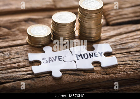 Nahaufnahme der Puzzleteile Geld sparen, indem Sie gestapelte Münzen auf Holz Stockfoto
