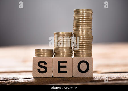 Nahaufnahme der SEO Text auf Holzklötze mit gestapelten Münzen geschrieben Stockfoto