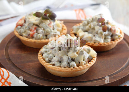 Törtchen mit Russischer Salat auf einem hölzernen Schneidebrett Stockfoto