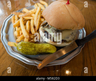 Ein Pilz und Schweizer Cheeseburger mit Pommes frites (Chips) und Dill Pickles bei Raindancer Restaurant serviert in Amsterdam, NY, USA Stockfoto