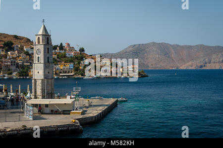 Der Uhrturm und die Einfahrt in den Hafen von Symi (Simi), eine kleine Insel der Dodekanes in Griechenland. Stockfoto