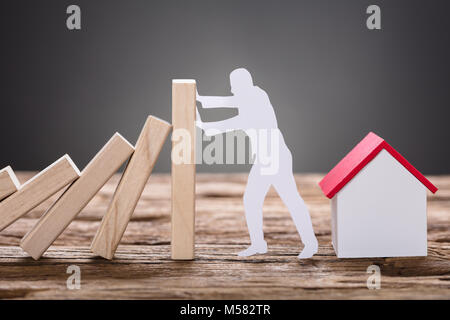 Nahaufnahme von Papier Mann stoppen Holz- domino Bausteine von Modell zu Hause auf dem Tisch Stockfoto