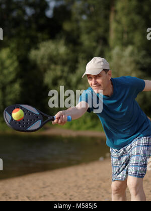Reifer Mann spielen Beach Tennis am Strand Stockfoto