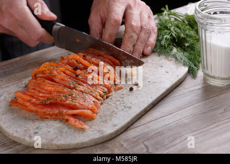 Kochen schneiden gesalzenen Lachs auf einem Schneidebrett Stockfoto