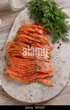 In Scheiben geschnitten gesalzen Lachsfilet auf einem Schneidebrett Stockfoto