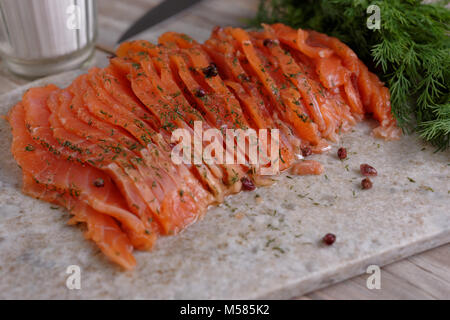 In Scheiben geschnitten gesalzen Lachsfilet auf einem Schneidebrett Stockfoto