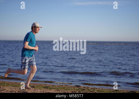 Barfuß reifer Mann beim Joggen am Strand Stockfoto