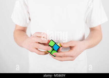 Teenager Geschwindigkeit 2x2 Würfel Puzzle im weißen T-Shirt mit weissem Hintergrund lösen Stockfoto